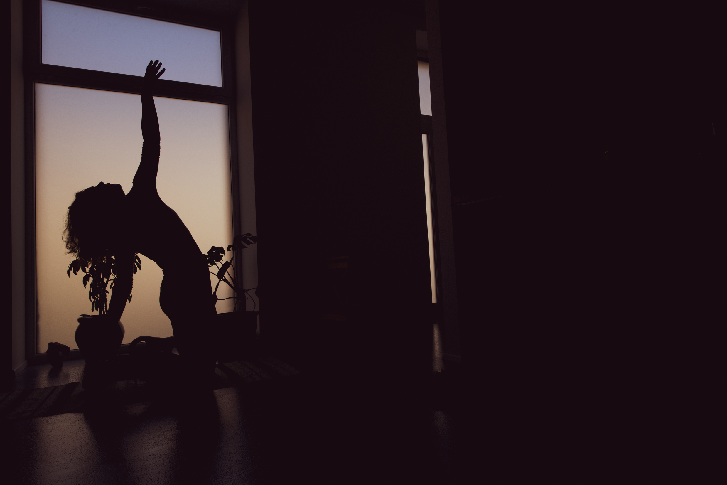 Silhouette of a woman doing yoga at home, embodiment and awareness through movement